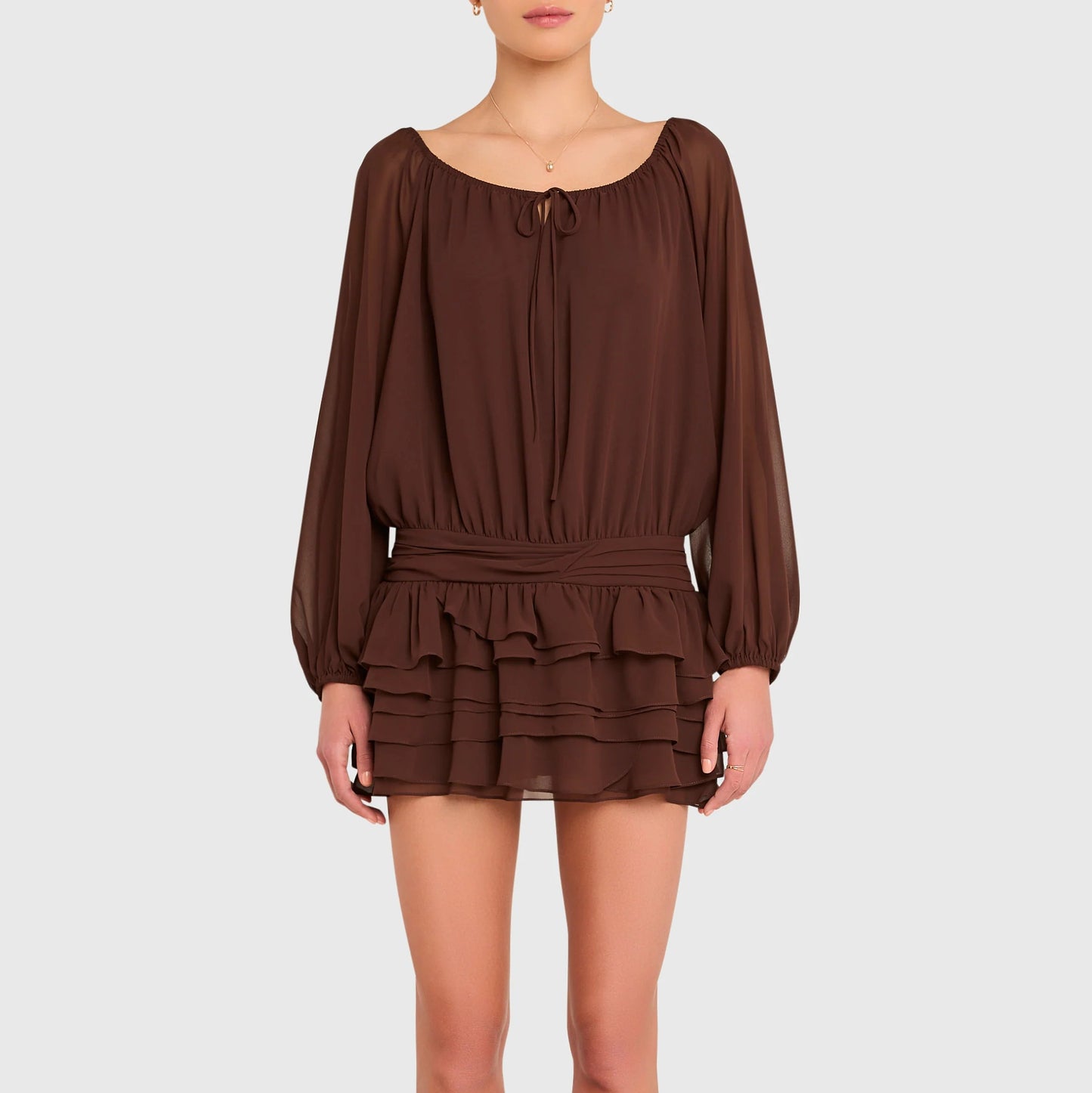 Brown dress with long sleeves and ruffled layers worn by a person on a white background. Dallas Romper Skort