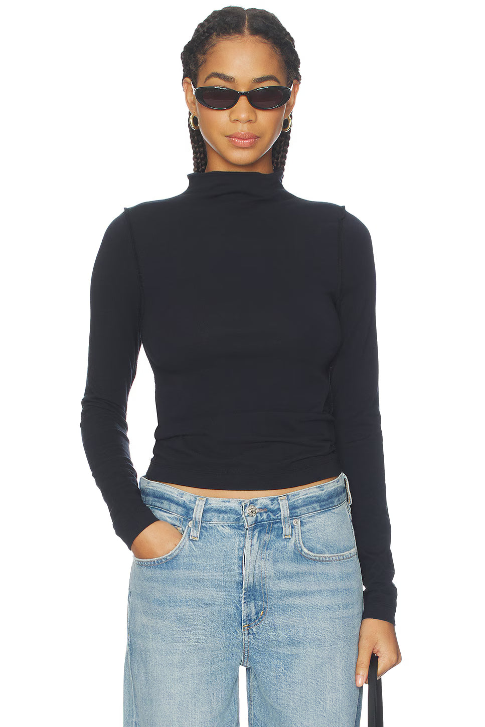 Person wearing a black turtleneck and blue jeans on a white background