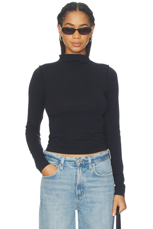 Person wearing a black turtleneck and blue jeans on a white background